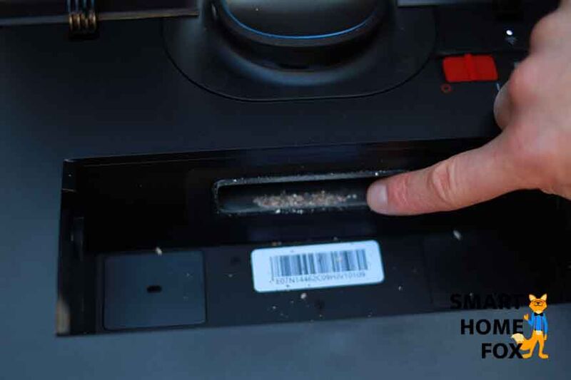 Ein Finger zeigt auf die Stelle vor dem Staubbehälter, wo sich beim Ecovacs Deebot T9 AIVI etwas Schmutz angesammelt hat